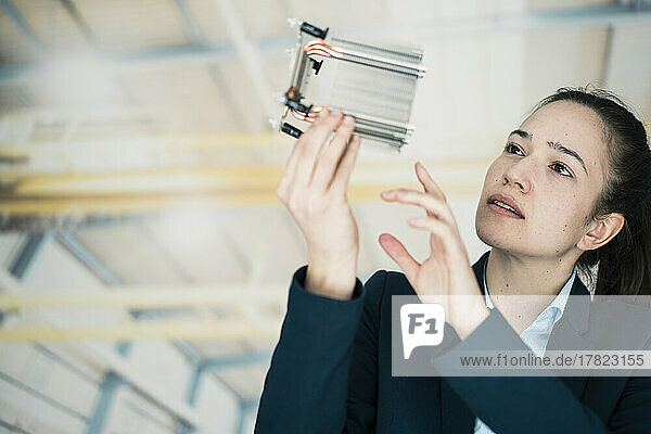 Businesswoman analyzing machine part in factory