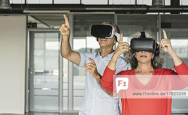 Businesswoman and businessman wearing virtual reality simulator gesturing in office
