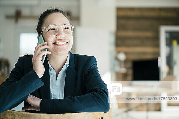 Happy businesswoman talking on phone at work place