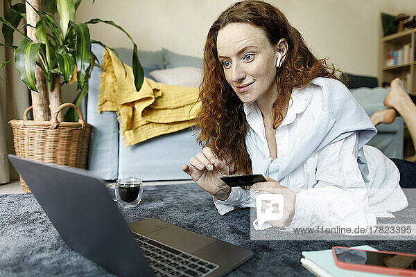 Happy woman with credit card making payment through laptop at home
