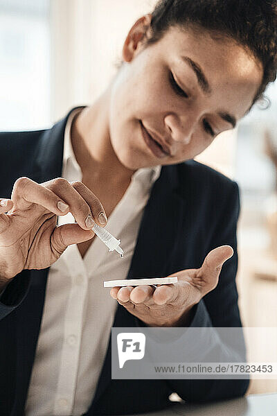 Smiling young businesswoman taking pregnancy test