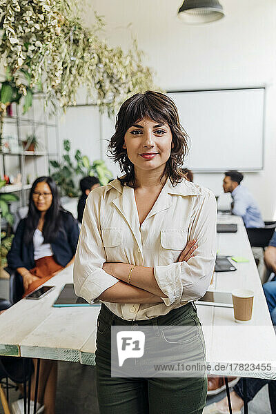 Confident businesswoman with arms crossed at coworking office