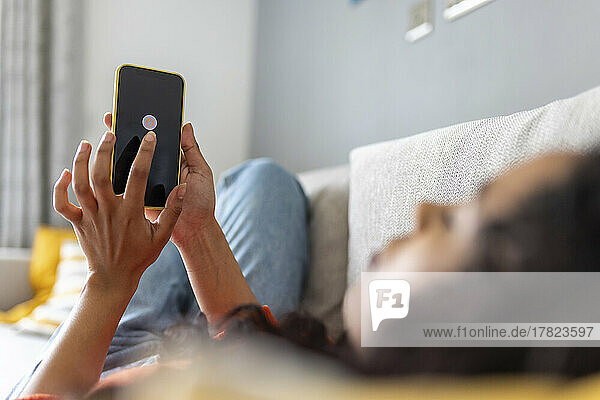 Woman turning off mobile phone using smart phone in living room