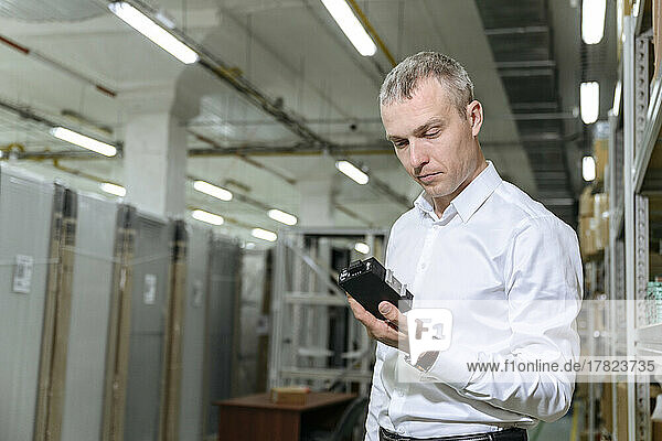 Businessman analyzing machine part in factory