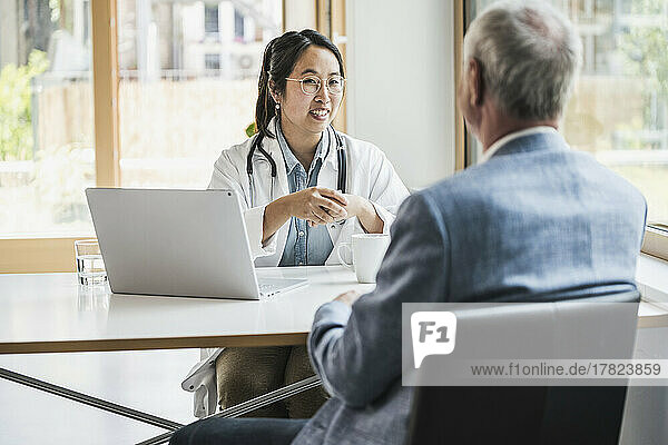 Happy female doctor discussing with patient in medical clinic