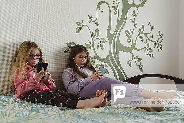 Schwestern benutzen Smartphone zu Hause im Bett