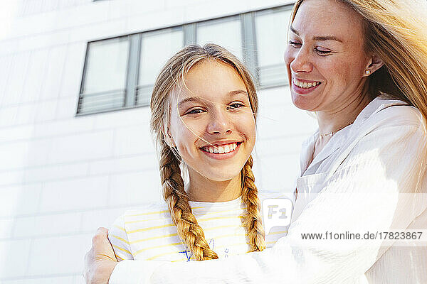 Glückliches Mädchen mit Mutter  die vor dem Gebäude steht