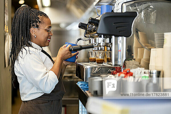 Smiling barista making coffee at restaurant kitchen
