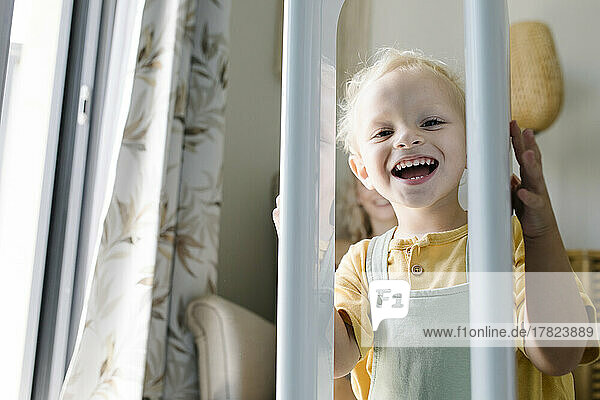 Happy boy looking through crib at home