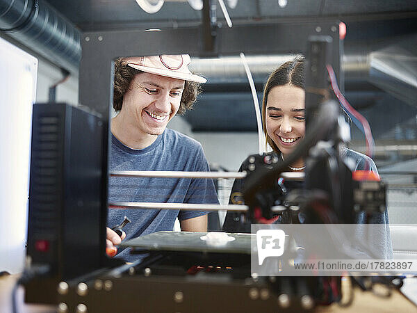 Smiling engineers working with 3d printer at workshop