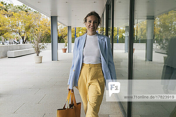 Happy businesswoman walking by glass window