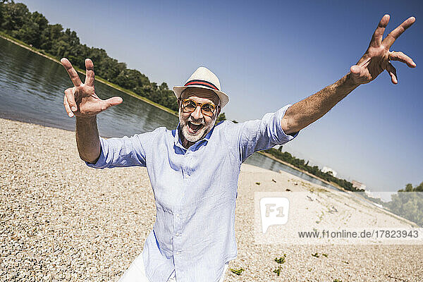 Playful senior man at riverbank on sunny day