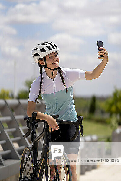 Lächelnder Radfahrer macht Selfie mit Smartphone im Park