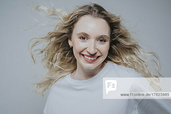 Happy blond woman smiling against grey background