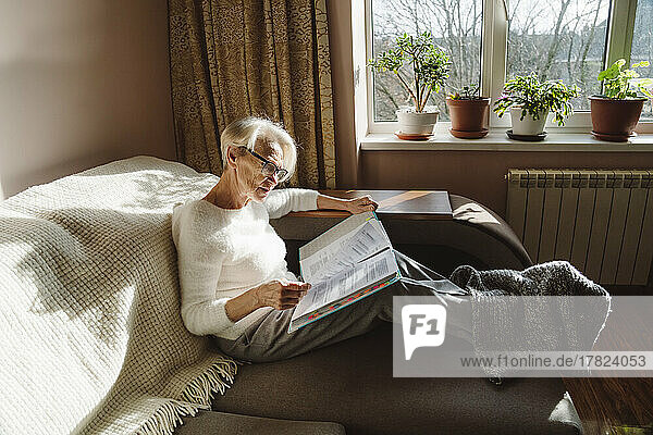 Woman wearing eyeglasses reading documents at home