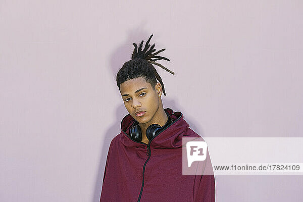 Young man with headphones against pink background