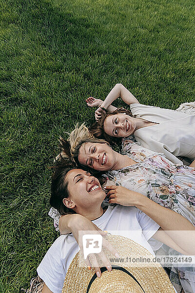 Happy young woman lying with friends at park