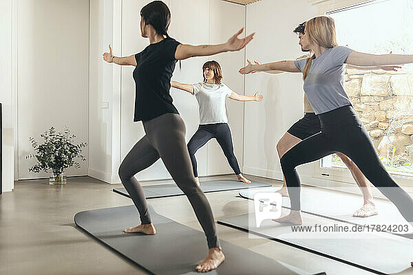 Man and women practicing yoga with instructor in health club
