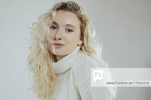 Young blond woman wearing turtleneck against white background