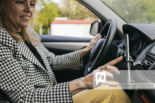 Smiling businesswoman using phone sitting in car