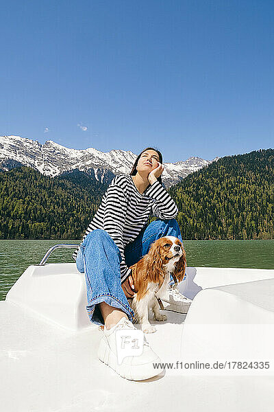 Woman with dog enjoying sunny day on boat at Lake Ritsa