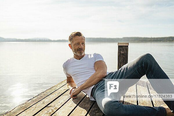 Mature man relaxing on pier at lake