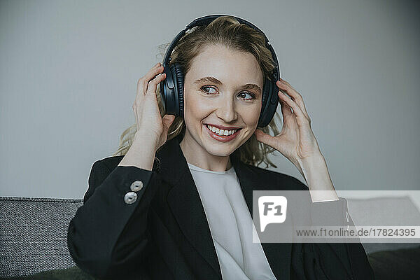 Contemplative businesswoman wearing wireless headphones