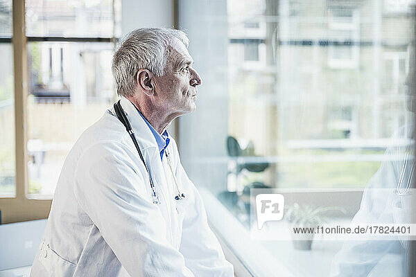Doctor looking out through window in hospital