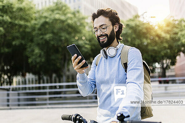 Glücklicher Mann mit Fahrrad und Mobiltelefon