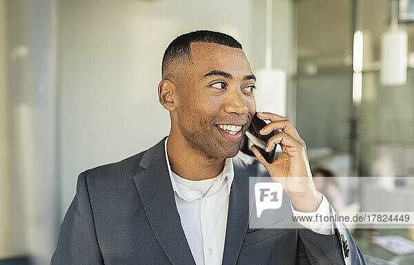 Contemplative businessman talking on smart phone at office