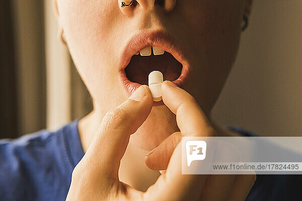 Woman with mouth open taking pill