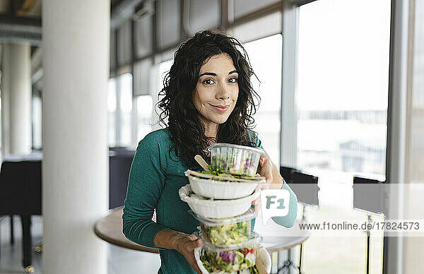 Smiling businesswoman with salad in office