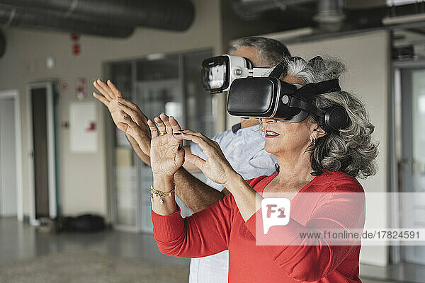 Happy businesswoman with colleague gesturing wearing virtual reality simulator