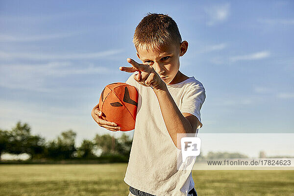 Boy with rugby ball gesturing on sunny day