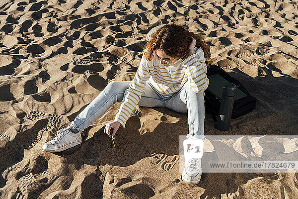 Junge Frau schreibt auf Sand am Strand