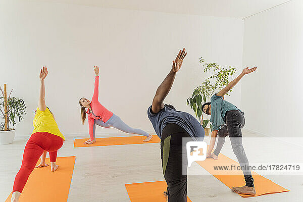Men and women doing Utthita Parsvakonasana exercise at yoga studio