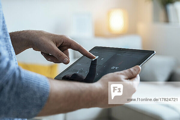 Hands of mature man using tablet PC in smart home