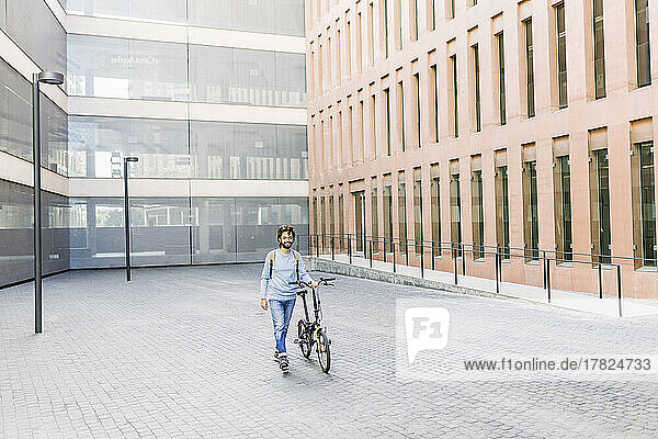 Smiling man with bicycle walking on street