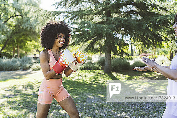 Happy Afro woman boxing by mother in park