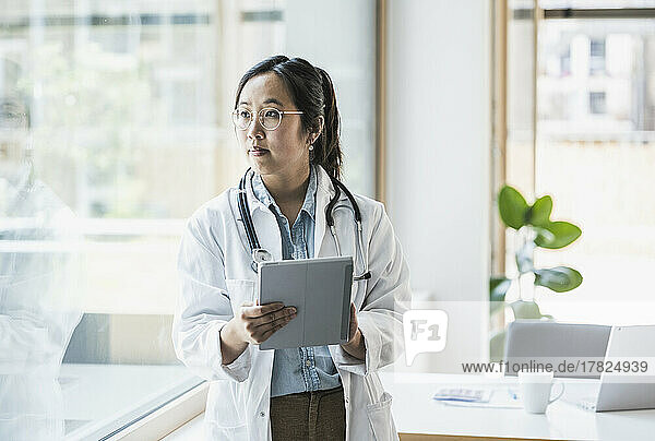 Female doctor with tablet PC standing in office