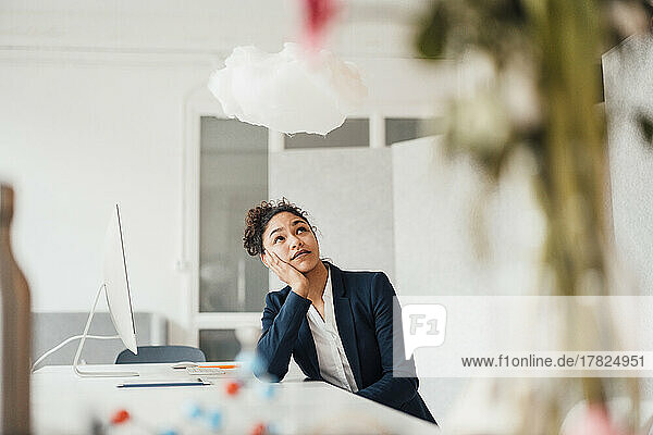 Thoughtful businesswoman looking at cloud in office