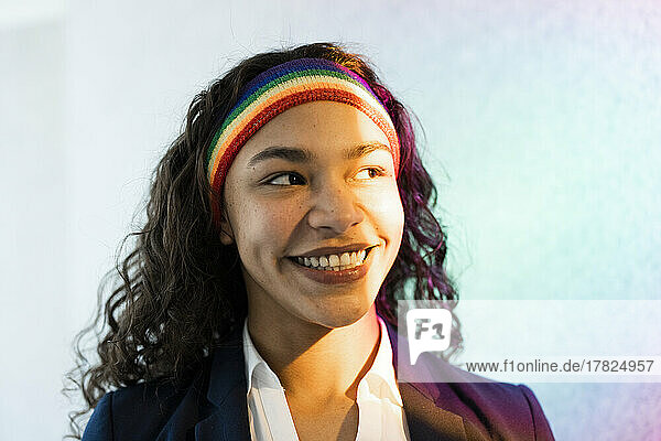 Happy young businesswoman with curly hair wearing multi colored headband