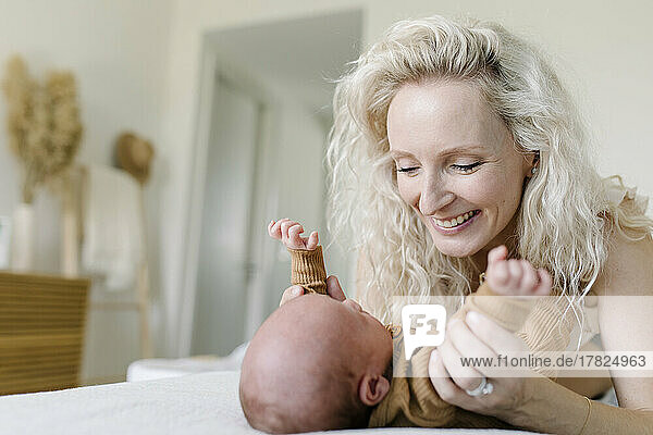 Happy woman playing with baby on bed at home