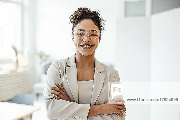 Happy businesswoman wearing eyeglasses standing in office