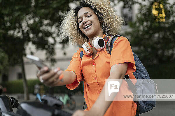 Smiling woman renting electric bicycle through mobile app