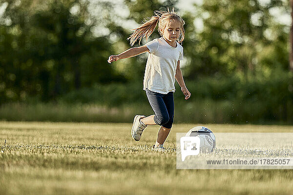 Blondes Mädchen spielt an einem sonnigen Tag Fußball