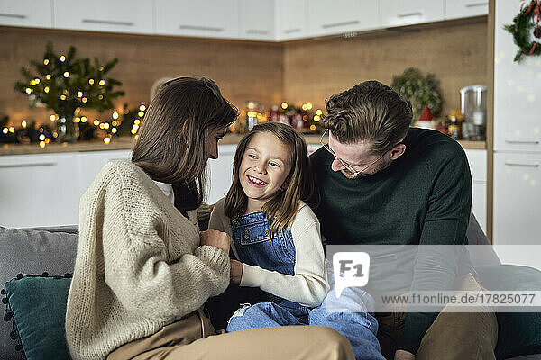 Smiling girl with parents sitting on sofa in living room