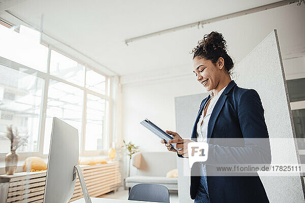Happy businesswoman using tablet PC at office
