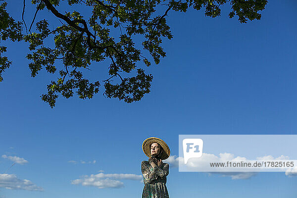 Girl wearing hat standing under tree
