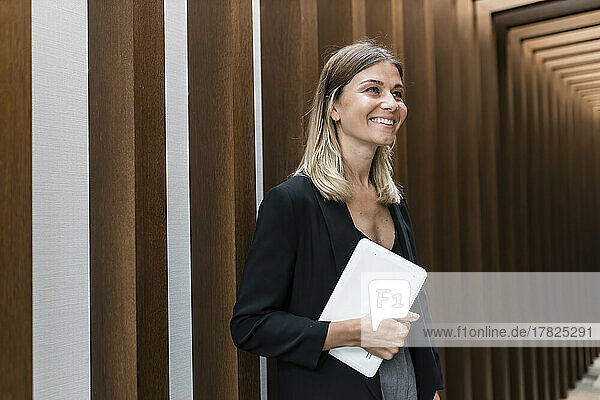 Happy businesswoman holding tablet PC Standing in corridor at hotel
